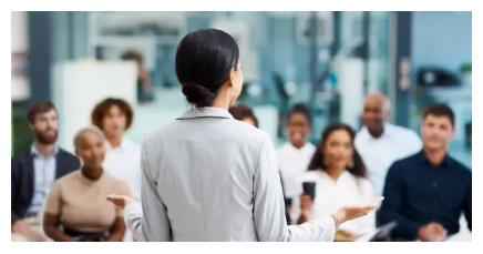 Uma mulher fala para um grupo de pessoas sentadas em um auditório