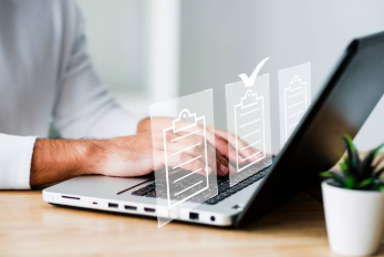 Uma pessoa em frente de um computador e planilhas sendo checadas virtualmente